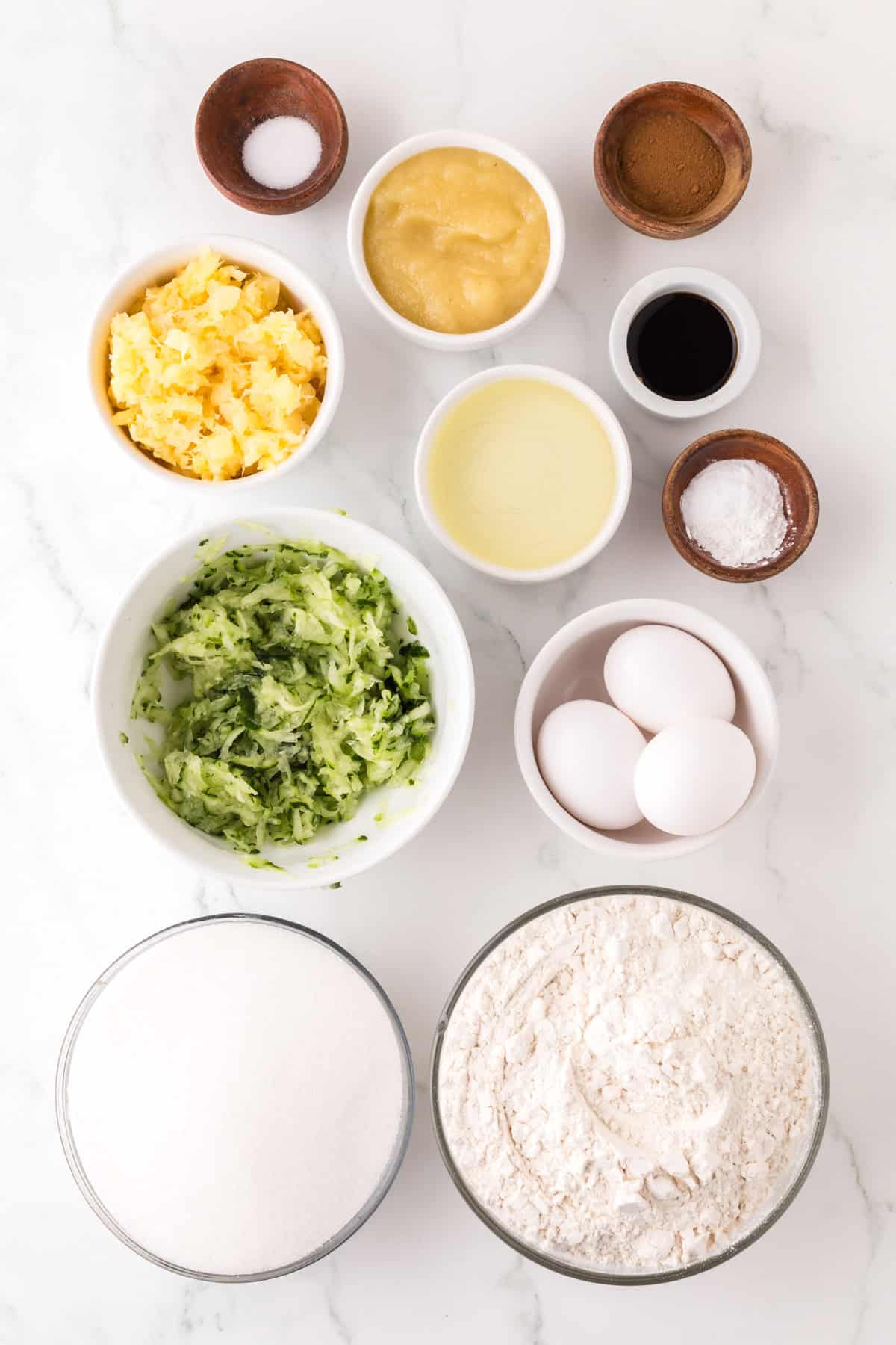 portion bowls each with raw ingredients to make pineapple zucchini muffins.