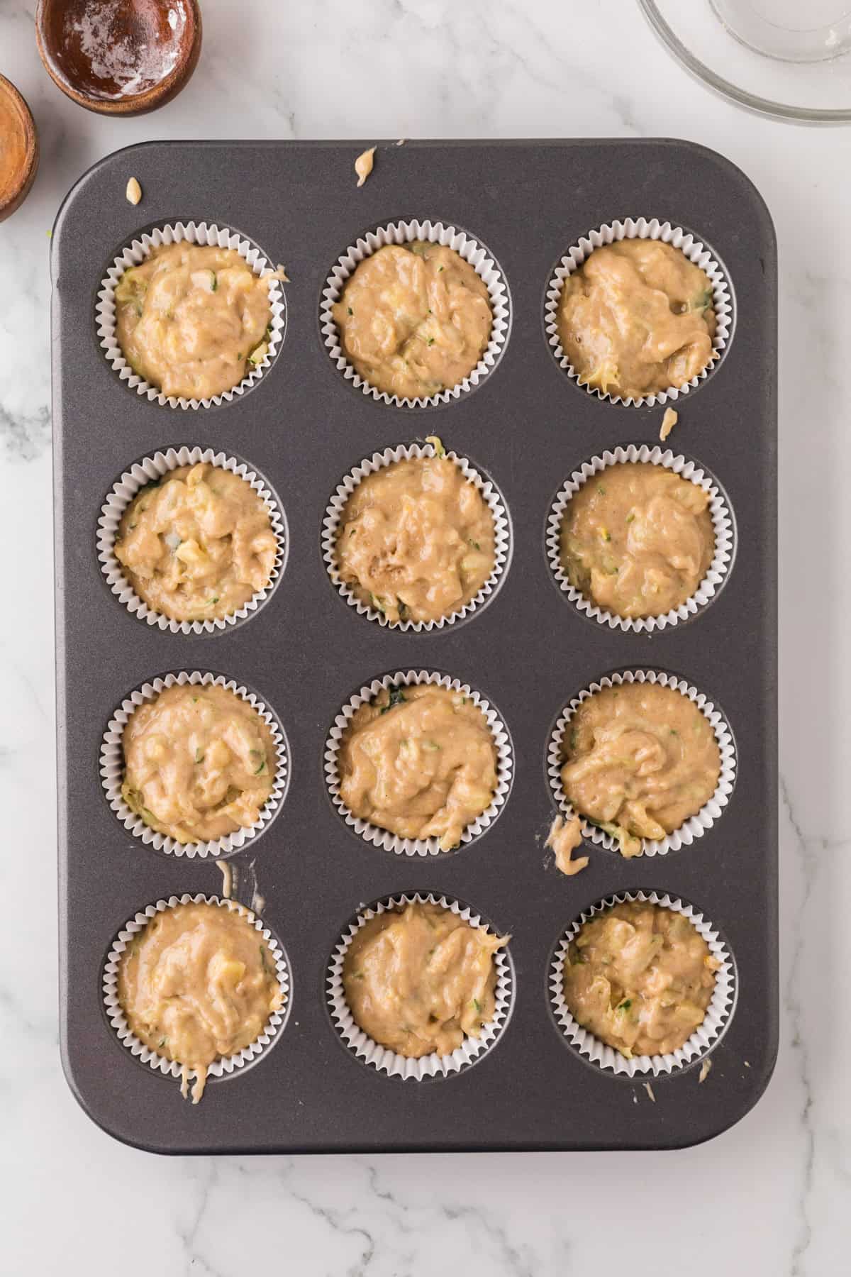 muffin tin with raw pineapple zucchini muffin dough.