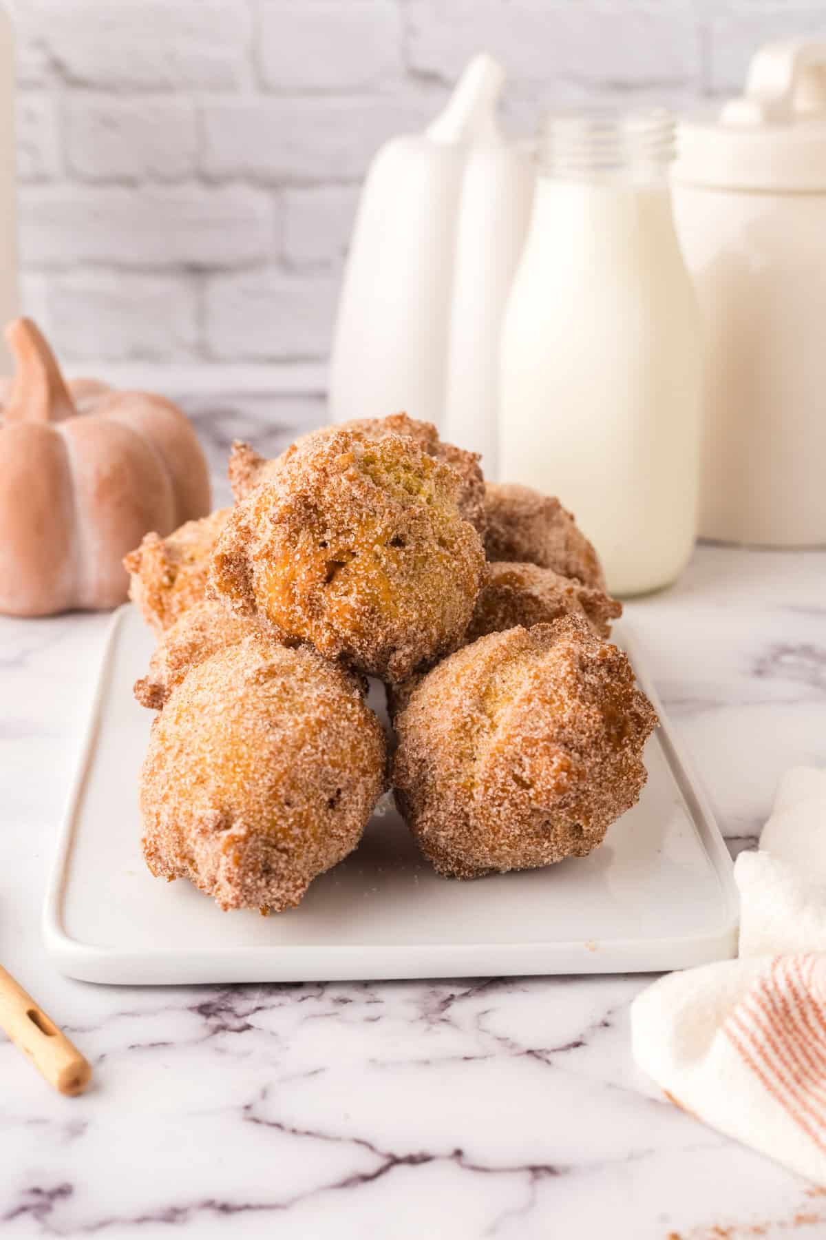 pumpkin donut holes in a pile on a square white plate.