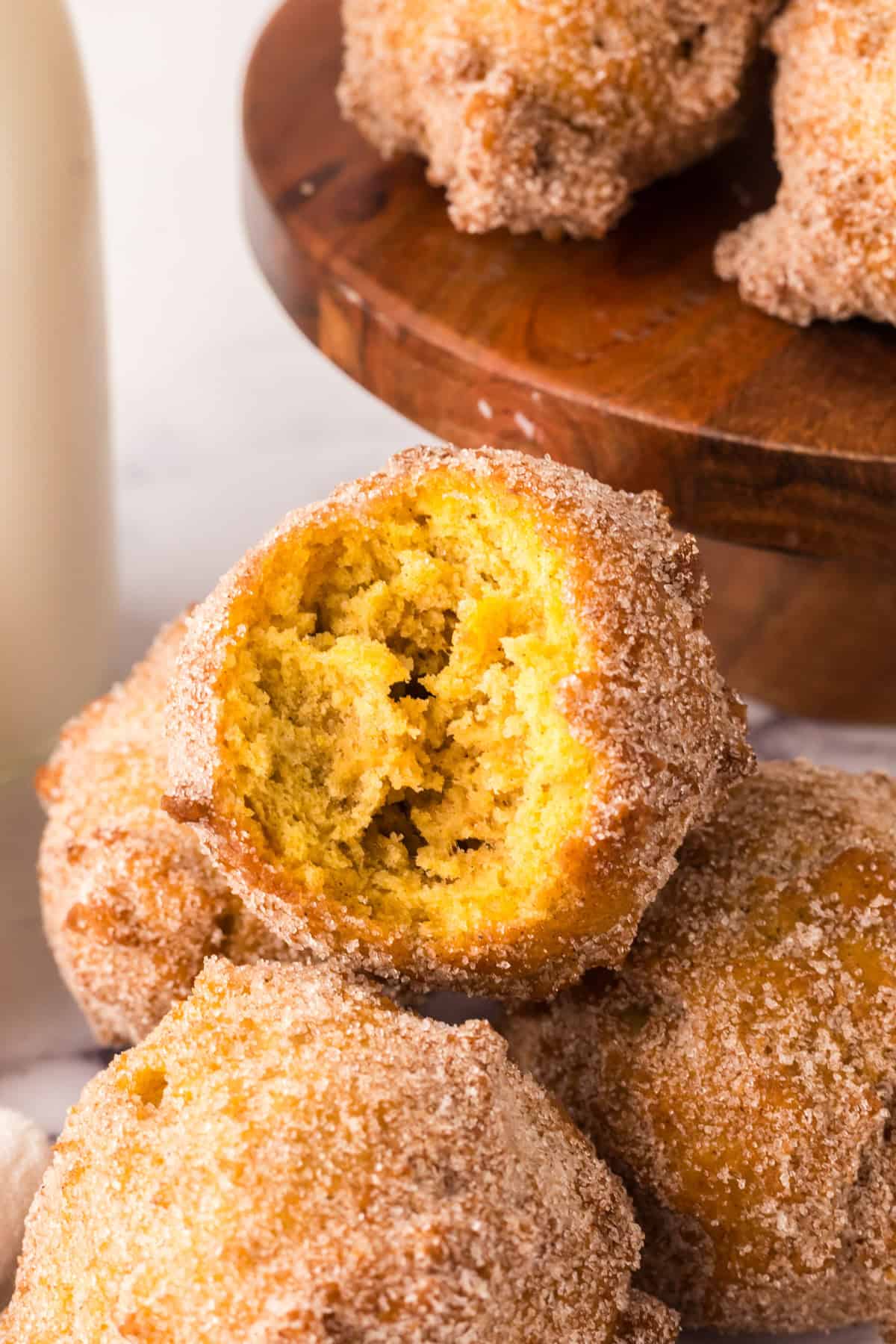 pumpkin donut holes in a pile with a bite out of one.