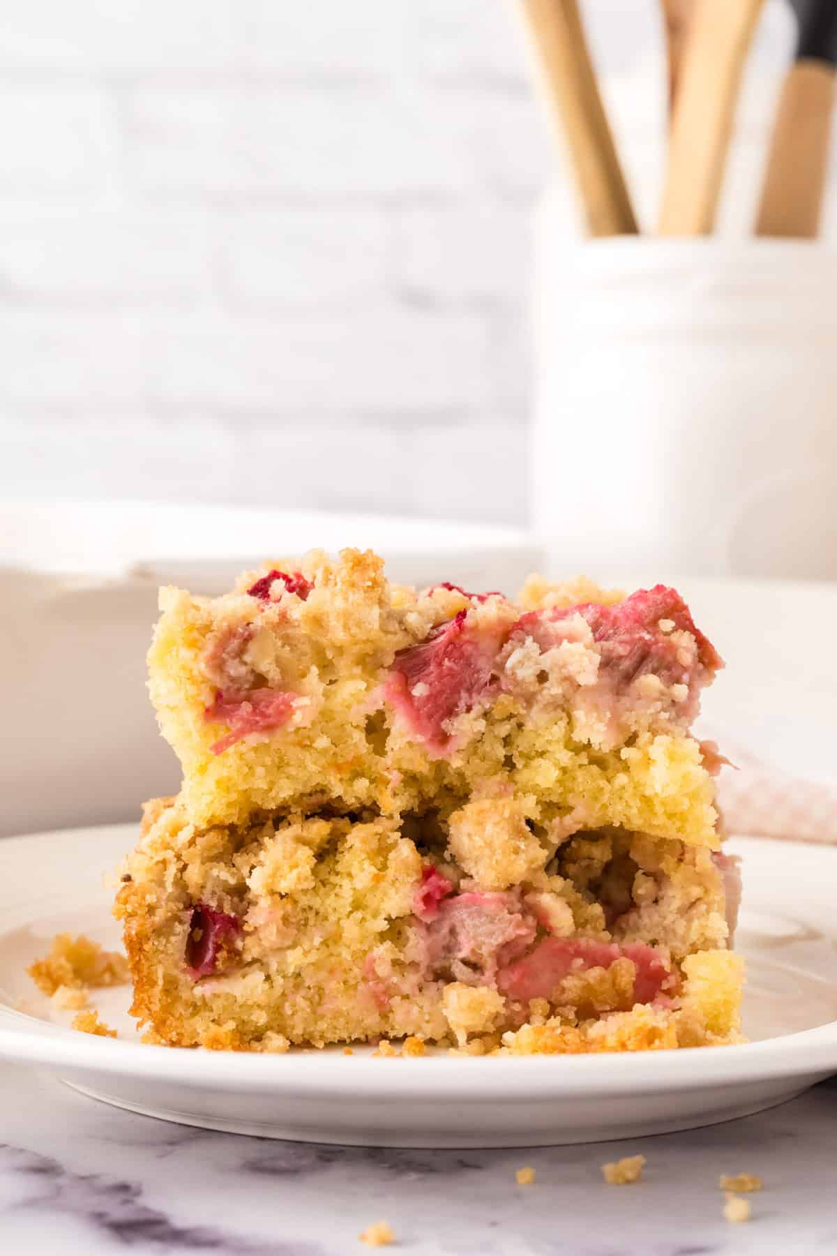 square portion of rhubarb crumble served on a round white plate.