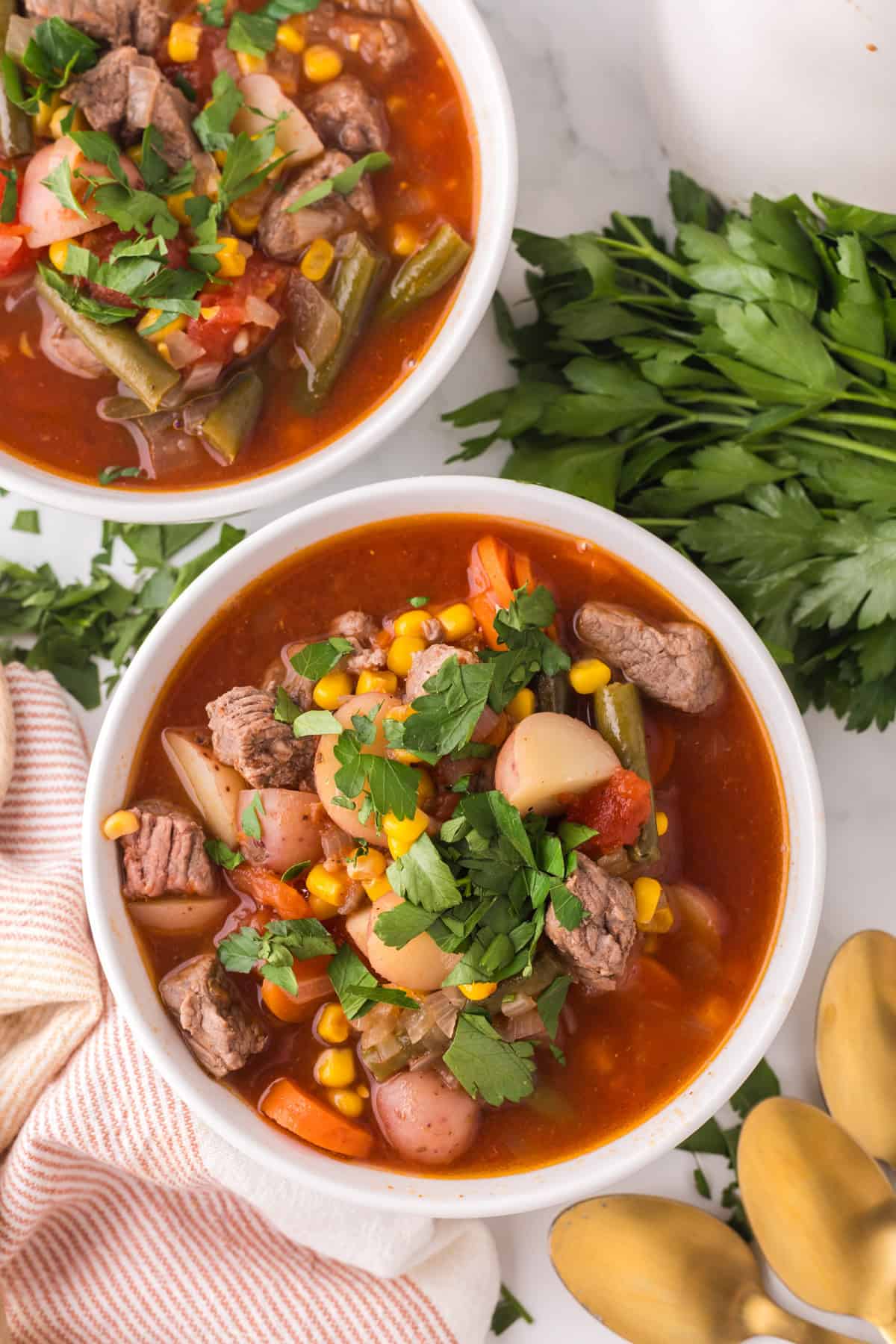 slow cooker beef veggie soup in white serving bowls.