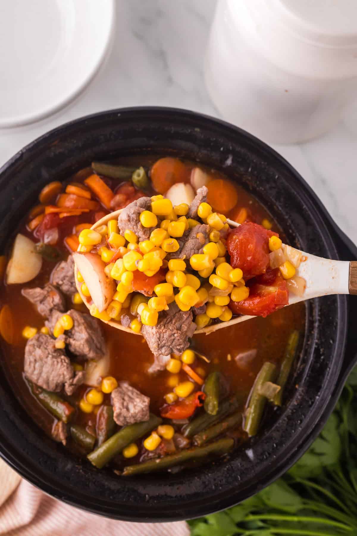 slow cooker beef veggie soup in progress inside the slow cooker.