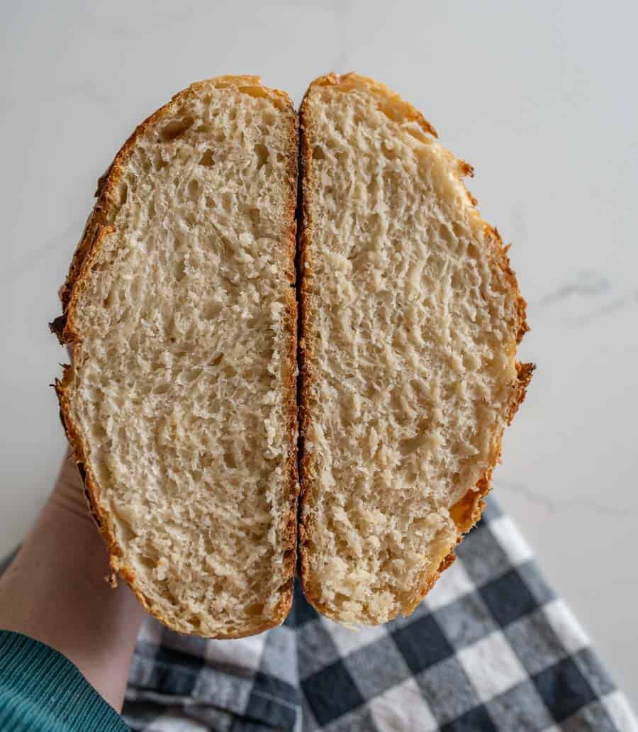 woman holding two slices of sourdough bread over black and white checkered towel. 