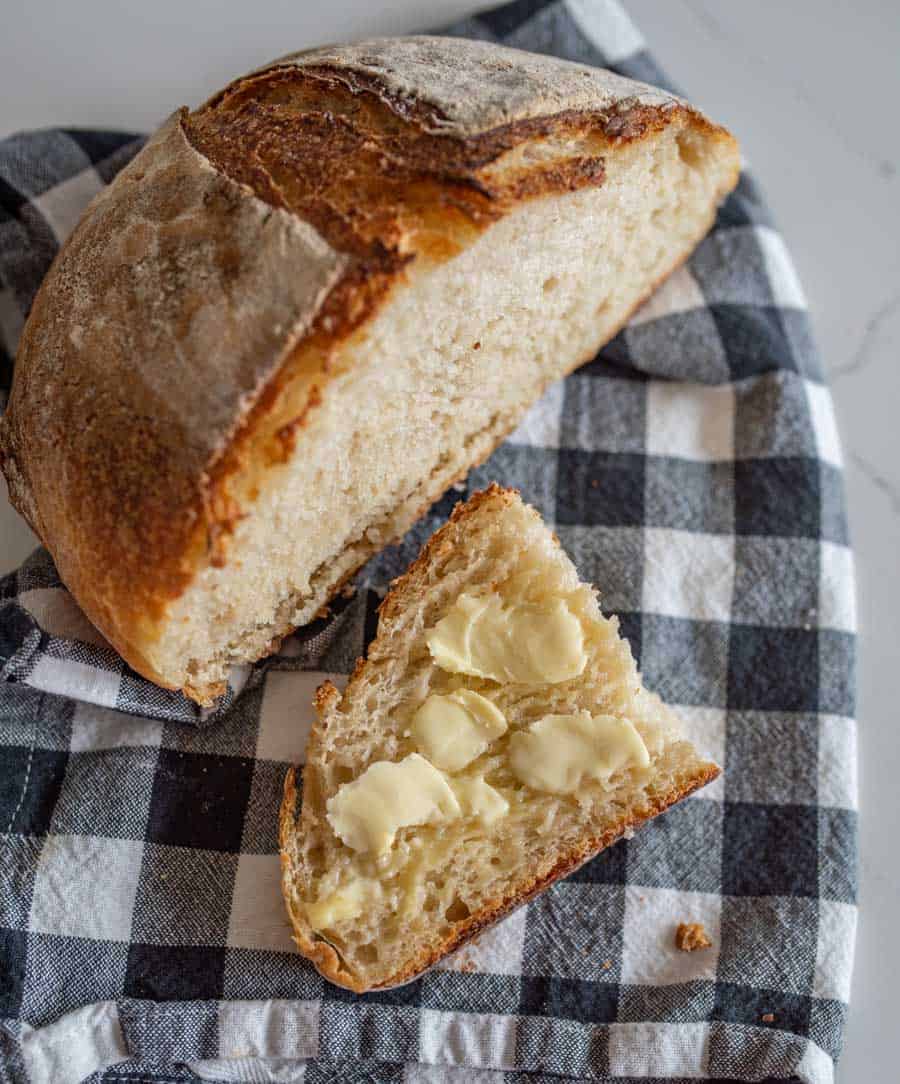 sourdough bread loaf with butter on black and white towel