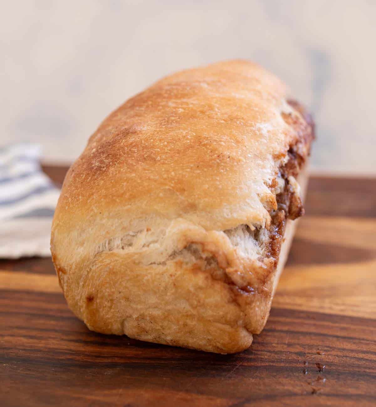 baked loaf of sourdough cinnamon swirl bread on brown board.