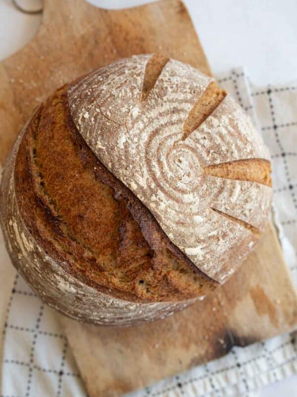 round loaf of sourdough rye bread on brown wooden board.