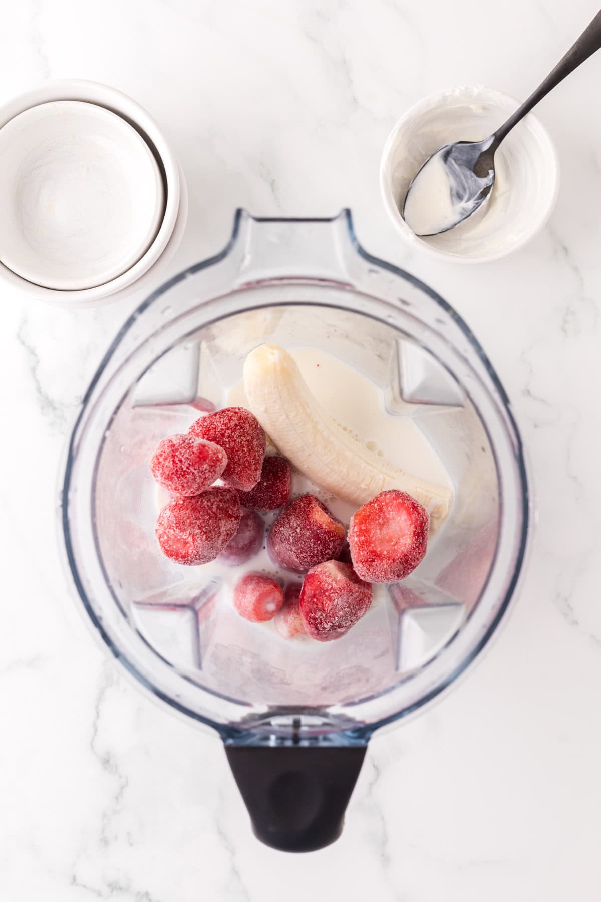 blender with strawberry kiwi smoothie ingredients inside.