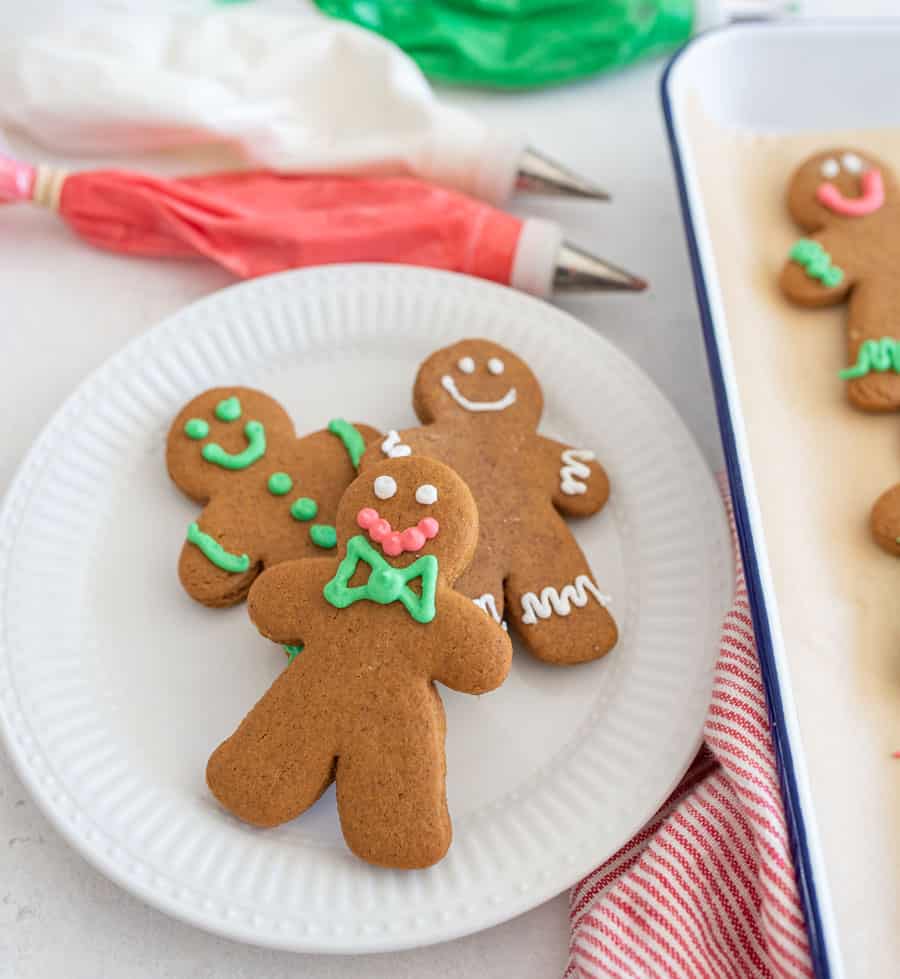 top view of traditionally decorated holiday ginger-people cookies on a white plate.