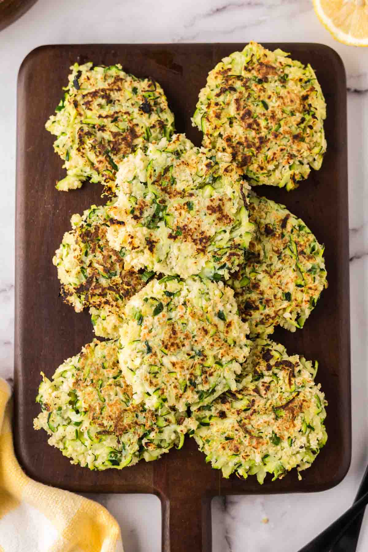 wooden board with a pile of zucchini fritters.